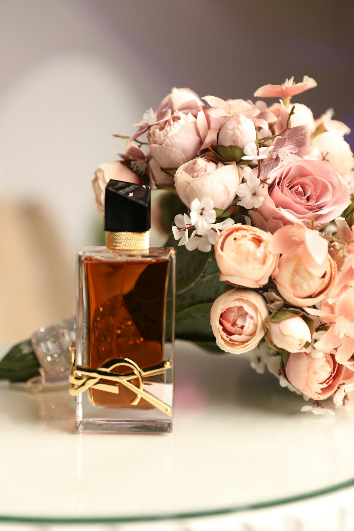 a bouquet of flowers sitting next to a bottle of perfume